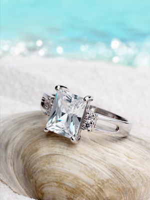 platinum diamond ring sitting on seashell with beach background